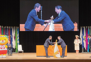 愛媛県中村知事から大会旗を受け取る平井知事の写真