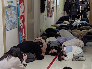 児童が校舎内で避難姿勢を取る写真